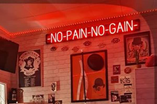 Custom tattoo shop sign touting “No Pain No Gain.”