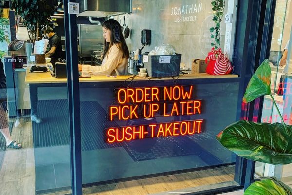 Neon sign that uses LED lights to spell out “Order Now Pick Up Later Sushi Takeout.”